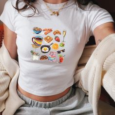 We love this fun, colorful Girl Breakfast Collage Baby Tee! This adult sized tee is soft and super comfy and is made of 52% cotton and 48% polyester for a luxurious lightweight stretch. The designs are printed with DTF which delivers a vivid, detailed design with a textured feel. This tee is a perfect blend of coquette fashion and nostalgic Y2K vibes, making it a trendy addition to your casual wardrobe. Made with soft, comfortable material, it's ideal for everyday wear or for making a statement Funny Print Graphic Tee Cropped T-shirt, Trendy Cropped T-shirt With Funny Print And Short Sleeves, Trendy Cropped T-shirt With Funny Print, Y2k Tops With Sublimation Print For Spring, Casual White Cropped T-shirt With Funny Print, Printed Short Sleeve Tops For Brunch, Cute Cropped Cotton T-shirt, 90s Style Crop Top T-shirt For Spring, 90s Cropped Summer T-shirt