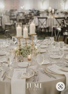 the table is set with white and gold plates, silver napkins, and candles