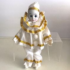 a small doll is dressed in white and gold