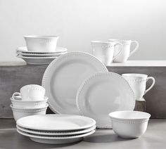 a table topped with white dishes and cups