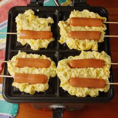 four hotdogs on skewers with scrambled eggs in a muffin pan