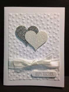 a white card with two hearts and a bow on the front that says happy together