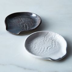 two white dishes sitting next to each other on a table