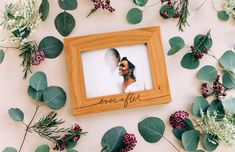 a wooden frame with the word ever after on it surrounded by leaves and flowers in front of a white background