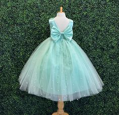 Our enchanting Ankle Length flower girl dresses are sure to turn heads! Bodice is made of Mint satin, waist consists of a matching sowed in sash (NOT DETACHABLE) The back of the dress has an open deep V-Back with a hidden zipper, followed by a detachable bow. The skirt has 4 Mint tulle layers for fullness, the top layer of tulle is ivory with ivory pearls. The dress has 2 layers of lining with crinoline. This dress is perfect for any occasion!  Dress Is Pictured with a petticoat NOT INCLUDED htt Princess Style Spring Wedding Ball Gown, Spring Wedding Princess Ball Gown, Spring Pageant Princess Dress With Bow, Pageant Princess Dress With Satin Bow And Tulle, Pageant Princess Dress With Satin Bow, Pageant Tulle Ball Gown With Satin Bow, Spring Green Princess Dress For Pageant, Green Princess Dress For Spring Pageant, Spring First Communion Tulle Gown