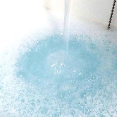 a blue tub filled with water next to a faucet