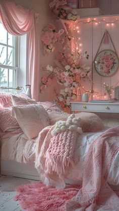 a bedroom decorated in pink and white with flowers on the wall, lights strung from above