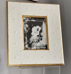 a white and gold frame hanging on the wall with a black and white photo in it