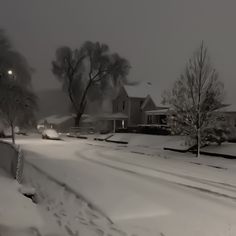 a snow covered street with houses in the background