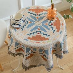 a round table with a blue, orange and white patterned cloth on it next to a plant