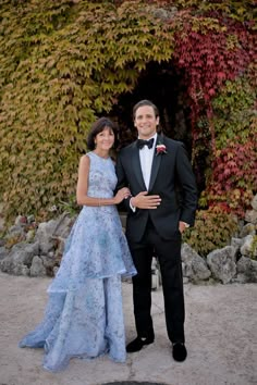 a man in a tuxedo standing next to a woman in a blue dress