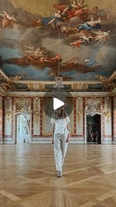 a woman walking through a large room with paintings on the ceiling