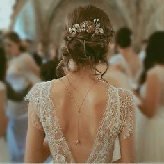 the back of a woman's dress with flowers in her hair and other people walking around