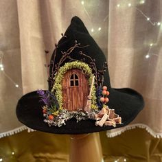 a black witch hat with an orange door and vines on the front, sitting on a wooden stand