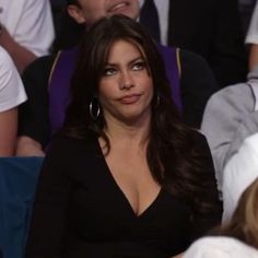 a woman in a black dress sitting next to other people