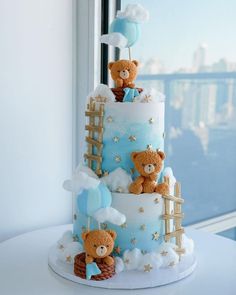 a three tiered cake with teddy bears on top and clouds in the sky above