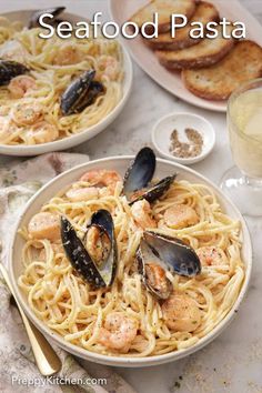 two plates of seafood pasta with clams and bread