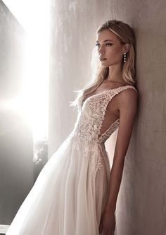 a woman in a wedding dress leaning against a wall