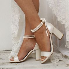 a close up of a person wearing high heel shoes with pearls on the ankle strap