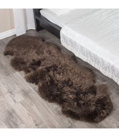 a brown sheepskin rug on the floor next to a bed