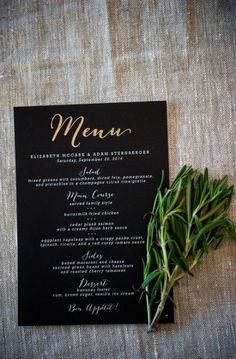 a black menu card sitting on top of a table next to a potted plant