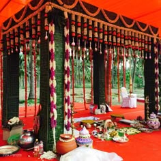 an outdoor wedding setup with flowers and garlands on the ceiling, in front of a tent