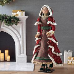 a woman in a red and green dress standing next to a fire place with candles