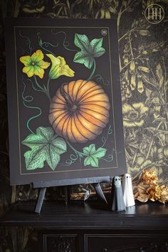 a painting on a table next to a vase with flowers and leaves painted on it