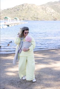 a woman holding a baby in her arms near the water