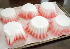 six pink and white cupcakes sitting on top of a sheet of wax paper