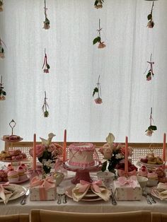 a table topped with lots of cakes and desserts covered in pink frosted icing