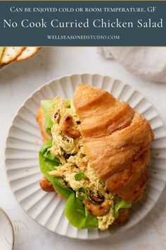 a croissant sandwich on a white plate with the words can be enjoyed cold or room temperature gf no cook currie chicken salad