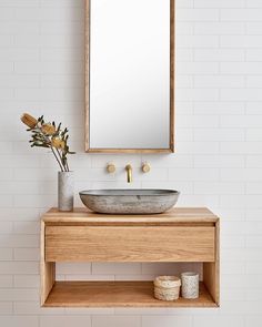 a bathroom with a sink, mirror and vase on the counter in front of it