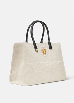 Crafted from canvas, this tote bag is adorned with a central La Medusa plaque and tonal debossed Versace logo lettering. The contrasting top handles are crafted from leather, and the spacious interior has two zipped pockets and a protector strap. Versace Bags Women, Versace Bag, Versace Logo, Versace Bags, Purse Styles, Large Tote Bag, Leather Items, Canvas Tote Bag, Large Tote