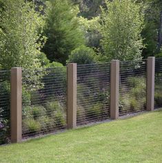 three tall wooden posts are next to a grassy area with trees and bushes in the background