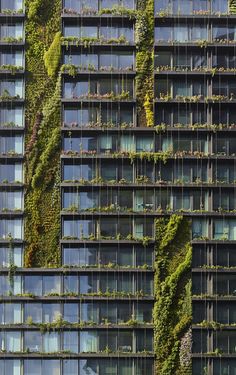 an office building with plants growing on the side of it's windows and balconies