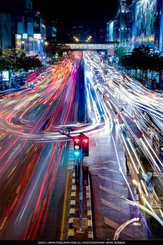 the city street is busy with cars and lights at night, as well as traffic