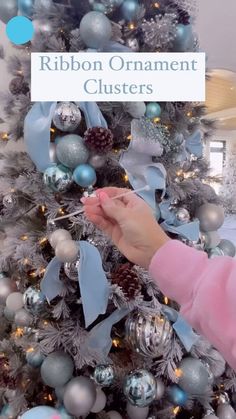 a woman decorating a christmas tree with blue and silver ornaments