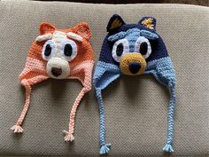 two crocheted hats with eyes and ears are sitting on a couch next to each other