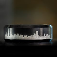 a wedding band with a city skyline etched on the inside of it, sitting on top of a table