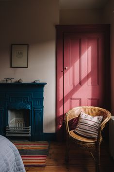 a chair sitting in front of a red door next to a bed and fire place