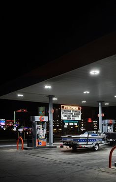 Gas station by night with a car and a boat. Station essence de nuit avec une voiture tractant un bateau. Aesthetic Gas Station, 2006 Aesthetic, 90's Aesthetic, Gas Money, Car Station, Building Aesthetic, Live Screen Wallpaper, Cars Music, Retro Background