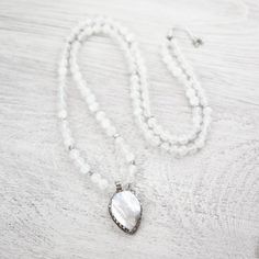 Less than 5 available. This limited edition DharmaShop exclusive mala features 108 high-quality Selenite beads from Morocco along with a handcrafted Mother of Pearl pendant from Nepal. Selenite is incredibly special with an energy like no other. Wearing this mala can help to cleanse negativity energy and bring clarity, relaxation and tranquility. A gorgeous piece of Mother of Pearl sits inside of an intricately hand carved silver-plated brass setting to create a stunning one-of-a-kind centerpiec White Adjustable Mala With Gemstone Beads, Adjustable White Gemstone Beads Mala, Adjustable White Mala With Gemstone Beads, Handmade White Mala For Healing, White Gemstone Beads Mala For Healing, Clear Negative Energy, Adjustable Knot, Energy Bracelets, Power Crystals