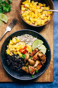 two bowls filled with food sitting on top of a wooden cutting board next to a knife and fork