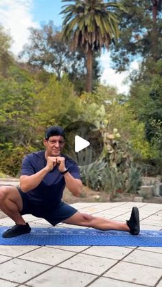 a man sitting on a blue mat with his legs crossed and one leg up in the air