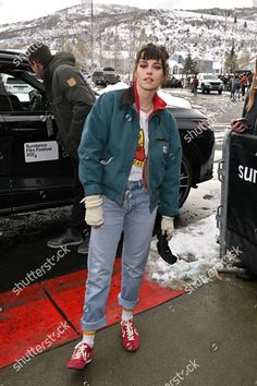 a woman standing in the snow with her hands on her hips and wearing red shoes