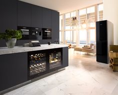 a kitchen with marble counter tops and an open wine cooler in the center, next to a dining room table