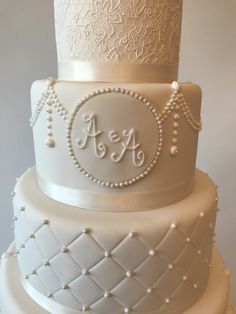 a three tiered white wedding cake with pearls