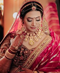 a woman in a red and gold bridal outfit is looking down at her hands