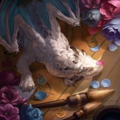 a dragon laying on top of a wooden table next to flowers and paintbrushes